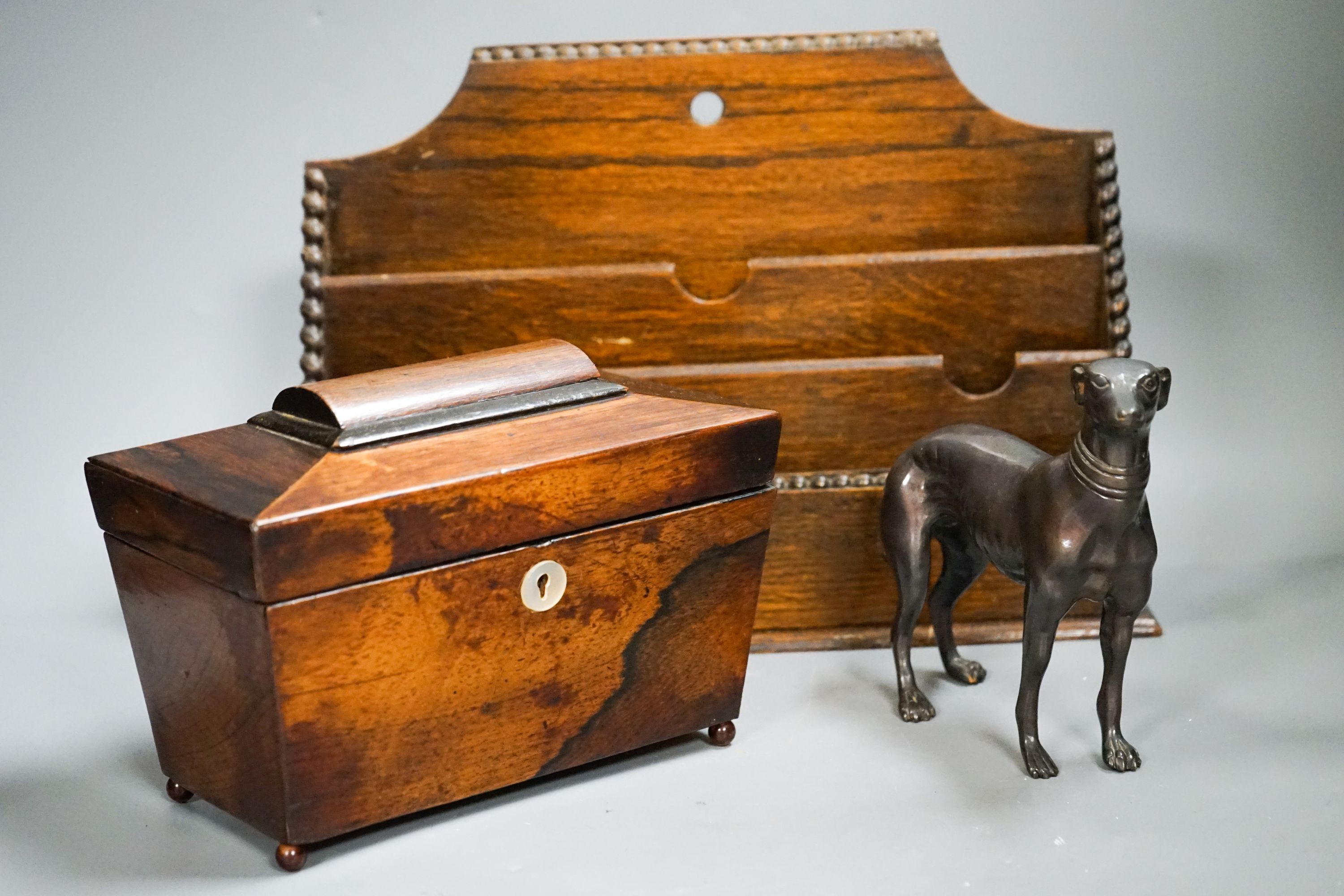 A bronzed metal greyhound, an Edwardian oak letter rack and a sarcophagus tea caddy.